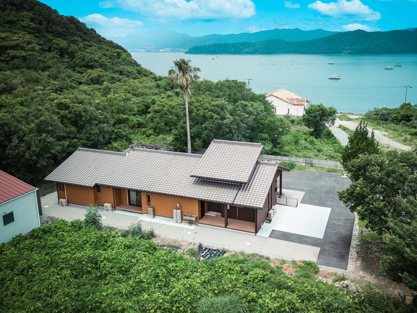 和風の屋根が印象的な木造住宅と、海の見える景色